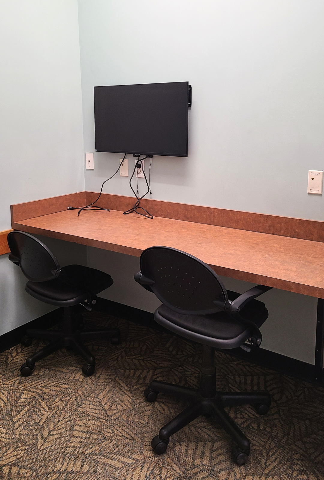 Small room with a desk, 2 chairs and a wall mounted screen